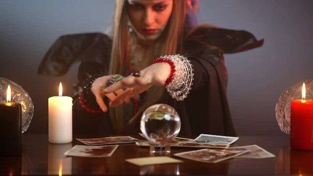 Witch with evil eyes talking with spiritual ghosts, spelling and firing someone's photo with candle fire, sorcerer holding potion spelling for death, evil rituals and witchcraft concept
