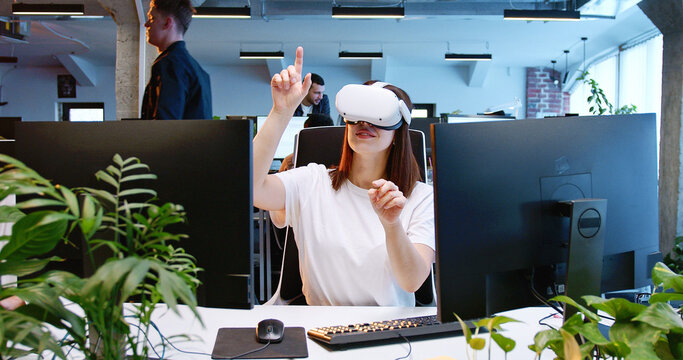Caucasian woman in VR glasses moving hands in air. Female in headset having virtual reality experience. Moving hands in air. Futuristic. Augmented. Call center of future. Coworking space.