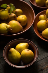 Ripe juicy pears in ceramic bowls on a dark