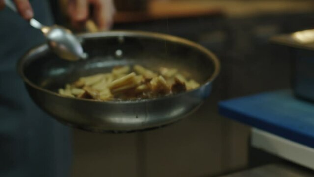 The cook is frying green string beans in a frying pan