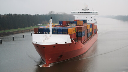 Kiel canal, Germany - 10 24 2022: Red color container vessel underway in the shipping channel