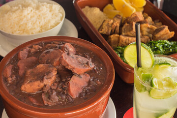 Brazilian feijoada with rice, cassava, crackling and lemon caipirinha