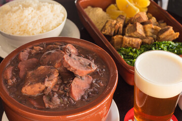 Brazilian feijoada with rice, cassava, crackling and cold beer