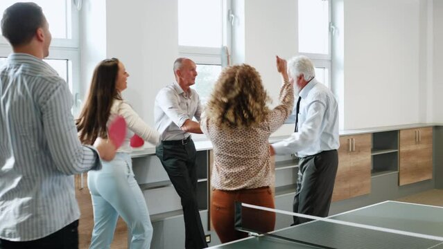 Employees And Colleagues Having Fun And Playing Table Tennis In Their Office Breakroom. 