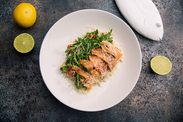 Salad with arugula, salmon, tomatoes, garnished with cheese and pine nuts