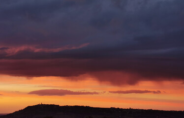Fototapeta na wymiar Rosso tramonto sul paese sopra la collina