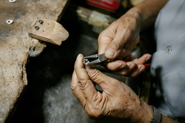 A craftsman is holding a stainless steel bracelet in his hand. At the desk. handmade concept The...