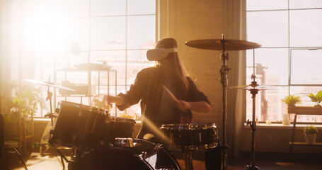Fototapeta na wymiar Portrait of a Young Female Wearing a Virtual Reality Headset, Playing Drums in at Home with Warm Sunlight. Drummer Girl Recording Herself Playing Music for Social Media Metaverse.