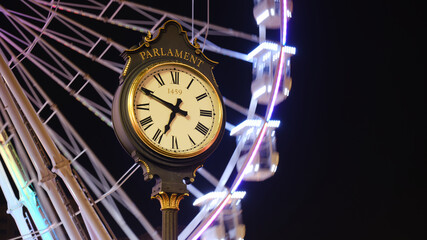 Bucharest Parliament public clock with Christmas ferris wheel in the back, at night. 1459, engraved...