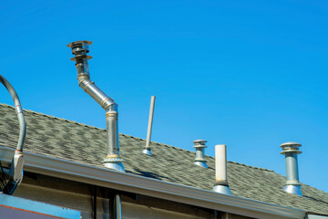 Chimney vents in rows on top of double gable style roof with gray pannels on top of house or home...