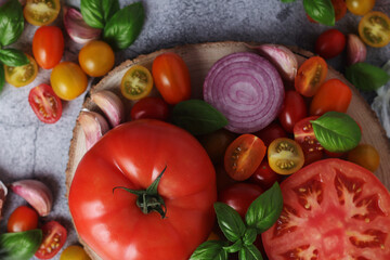 Flat lay composition of different tomatoes, onion, basil and garlic