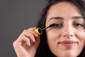Using mascara, beautiful caucasian woman using mascara on eyelash. Close up cropped frontal face...
