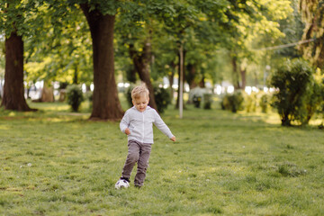 Fototapeta premium cute little boy play a football outdoors