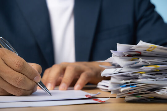 Business man hand writing with Stack of Group report papers Document clipped in color clips.