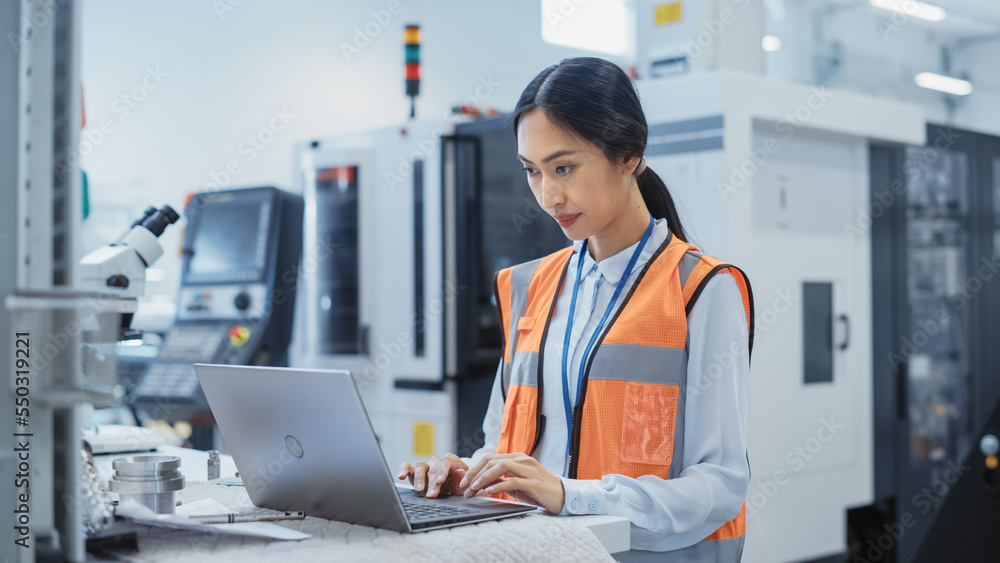 Leinwandbilder portrait of an asian female engineer in orange safety vest working on laptop computer at electronic 