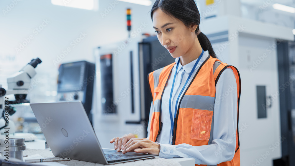Poster research and development specialist using laptop to operate a heavy industry machine at a factory. a