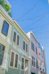 Houses with outdoor string lights against blue sky background on a sunny day.