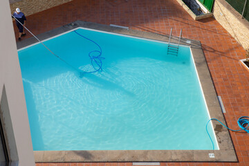 Man cleaning the swimming pool with vacuum equipment. swimming pool cleaning. a man is cleaning the pool. service care