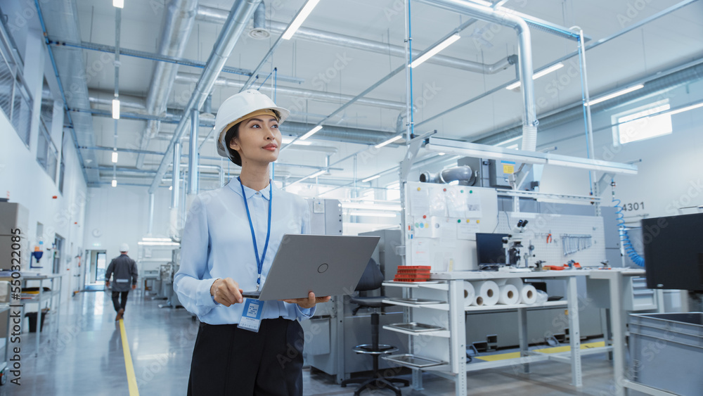 Fototapete Portrait of an Asian Female Engineer in Hard Hat Standing and Using Laptop Computer at Electronic Manufacturing Factory. Technician Thinking About Daily Tasks and Working on Development Data.