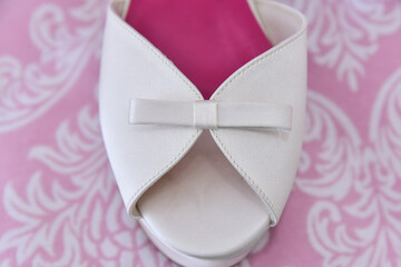 white sandal with bow on pink background
