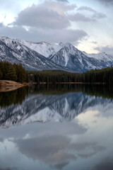 Snow covered Rocky Mountains in Banff National Park in Canada, reflect on the calm lake water.