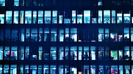 Pattern of office buildings windows illuminated at night. Glass architecture ,corporate building at night - business concept. Blue graphic filter.