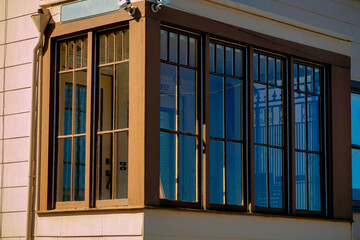 Brown wrap around window with visible glass and pink wooden exterior on the face of house or home in a suburban area downtown