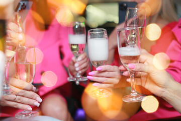 hands with champagne.Girls are celebrating in limo.girls in pink clothes in a limo drinking champagne