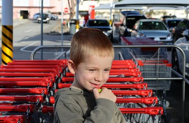 The short-haired, blond boy looks down shyly. A embarrassed five-year-old boy.  
