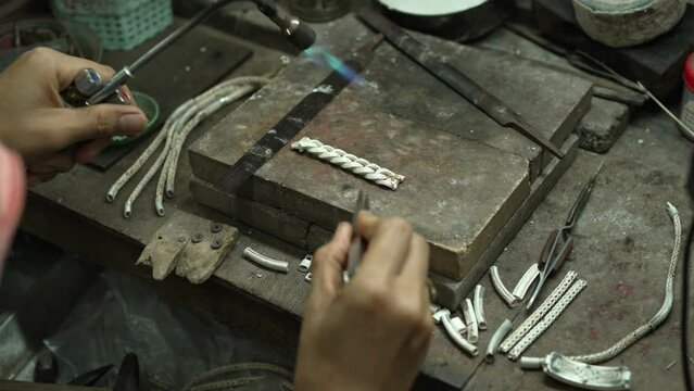 A craftsman is making a bracelet in his hand. At the desk. handmade concept The bracelet is made of real silver.