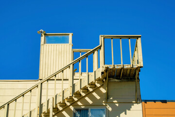 Stairs leading to the roof of the house to a flat patio with beige or yellow paint with blue dark sky in the late afternoon sun