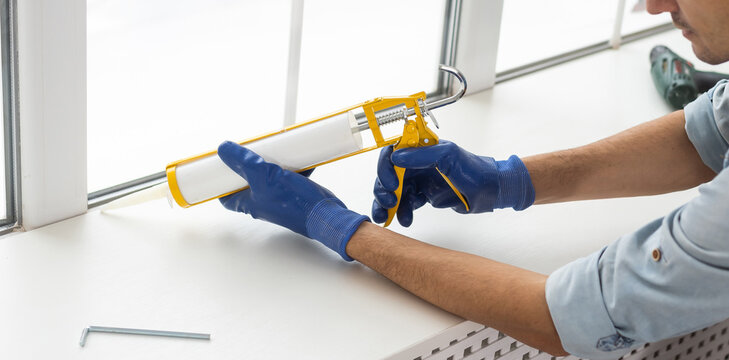 Construction Worker Sealing Window With Caulk Indoors