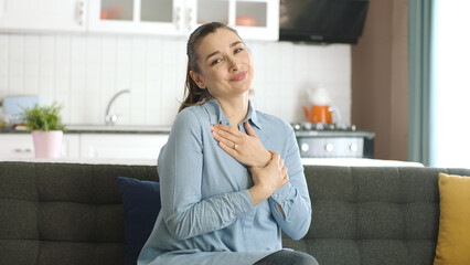 Smiling young woman at home showing her solitaire ring to the camera with her hands. Marriage...