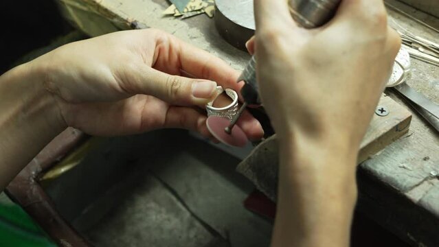 A craftsman is holding a gemstone ring in his hand. At the desk. handmade concept The ring is made of real silver.