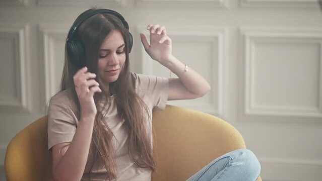 beautiful young teenage girl is wearing headphones and listening to music, portrait at home