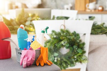 Cleaning before Christmas. Multicolored cleaning supplies. Sponges, rags and spray with festive decorations against modern home background.