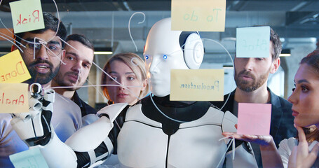 Diverse team of project discussing plans and to-do notes with robot. Teambuilding of multiethnic...