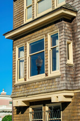 Street lamp visible in window reflection on brown wooden house with slatted wooden pannels in the downtown urban neighborhood