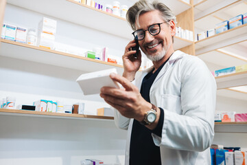 Naklejka na ściany i meble Pharmacist reading a medication label and talking on the phone