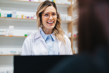 Woman assisting a patient over the counter in a pharmacy