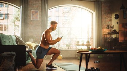 Obraz premium Strong Athletic Black Man Does Shirtless Workout at Home, Single Leg Squatting while Using Smartphone. Fit Muscular Sportsman Staying Healthy, Training Mind, Body and Doing e-Commerce Work on Mobile