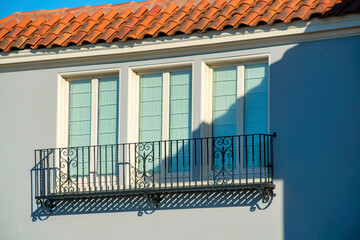 Blue stucco house with red or orange adobe roof tiles and black balcony with white accent paint...