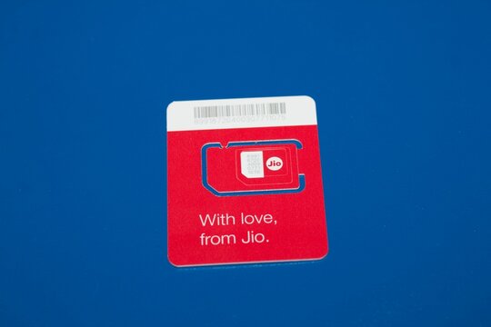 Closeup of an Indian red Jio SIM with a blue copy space on the background