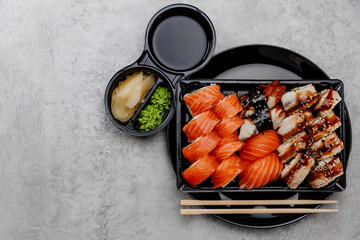 A set of four types of sushi in a black box with vossabi sauce and ginger on a gray background.Top view
