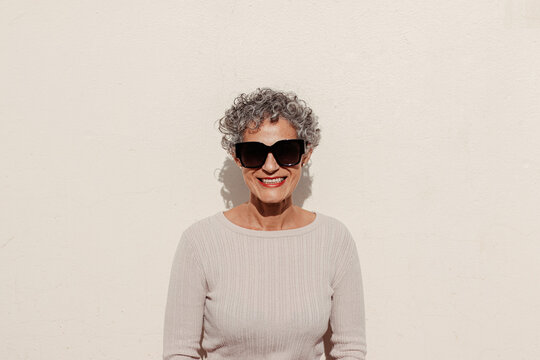 Mature woman against sunlit wall