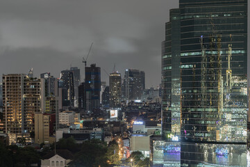 Obraz na płótnie Canvas Skyscrapers in the business district of Bangkok city at night under Sprinkling rain. Rainy season, No focus, specifically.
