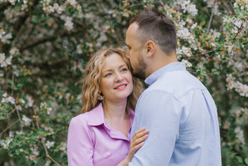 Fototapeta premium Man kisses his woman in blooming gardens in spring