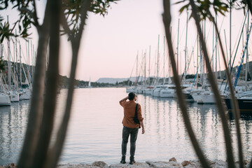 A young, stylish man in sunglasses at the marina among the sea yachts.