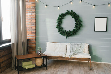 Christmas wreath over the sofa in the living room in a Scandinavian minimalist style. Mockup of a painting on the wall