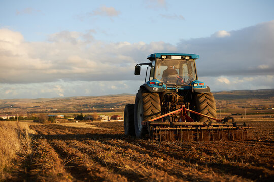 Tractor with plow working soil of agricultural field